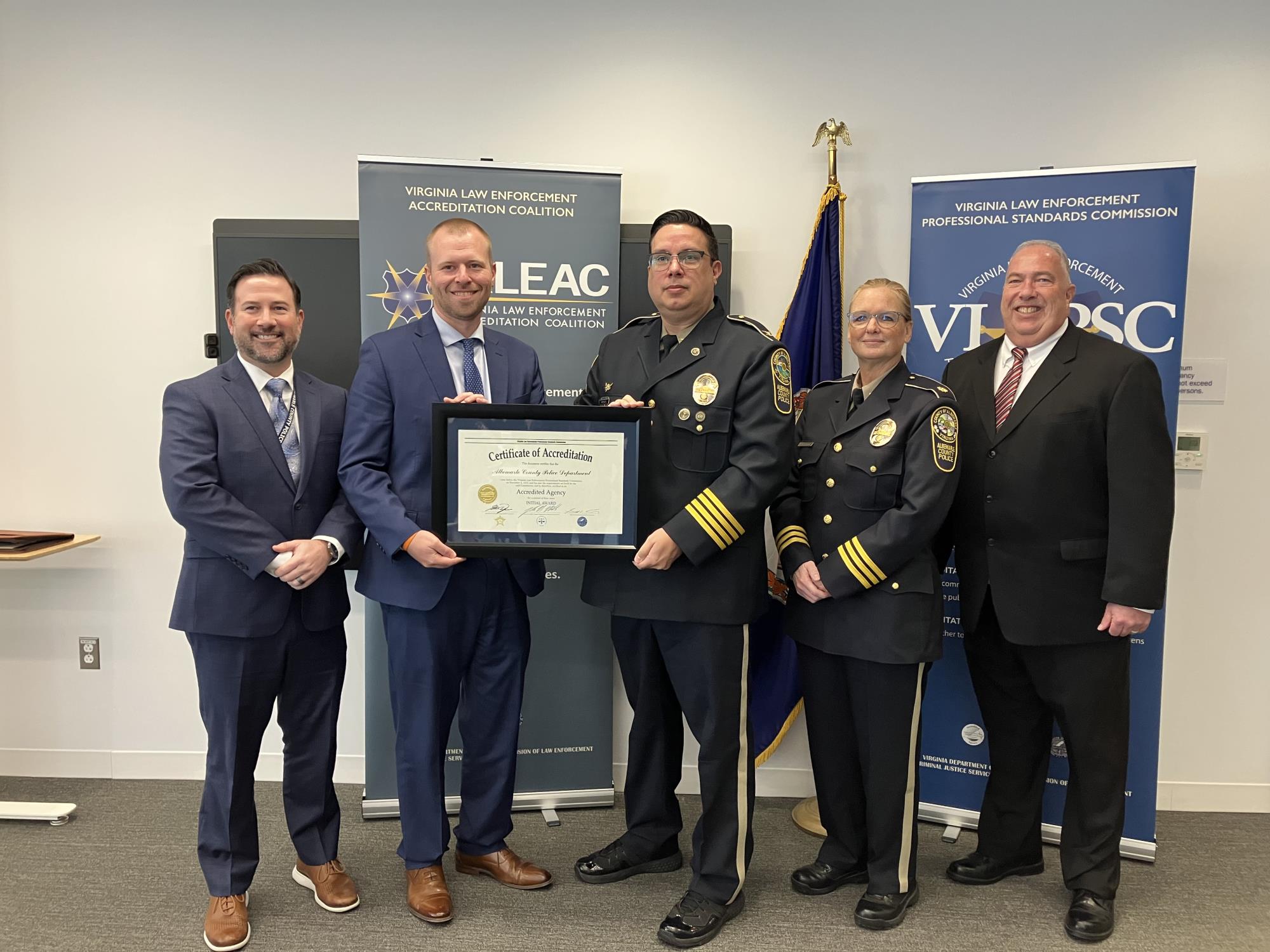 4 people standing in front of a US flag holding a certificate